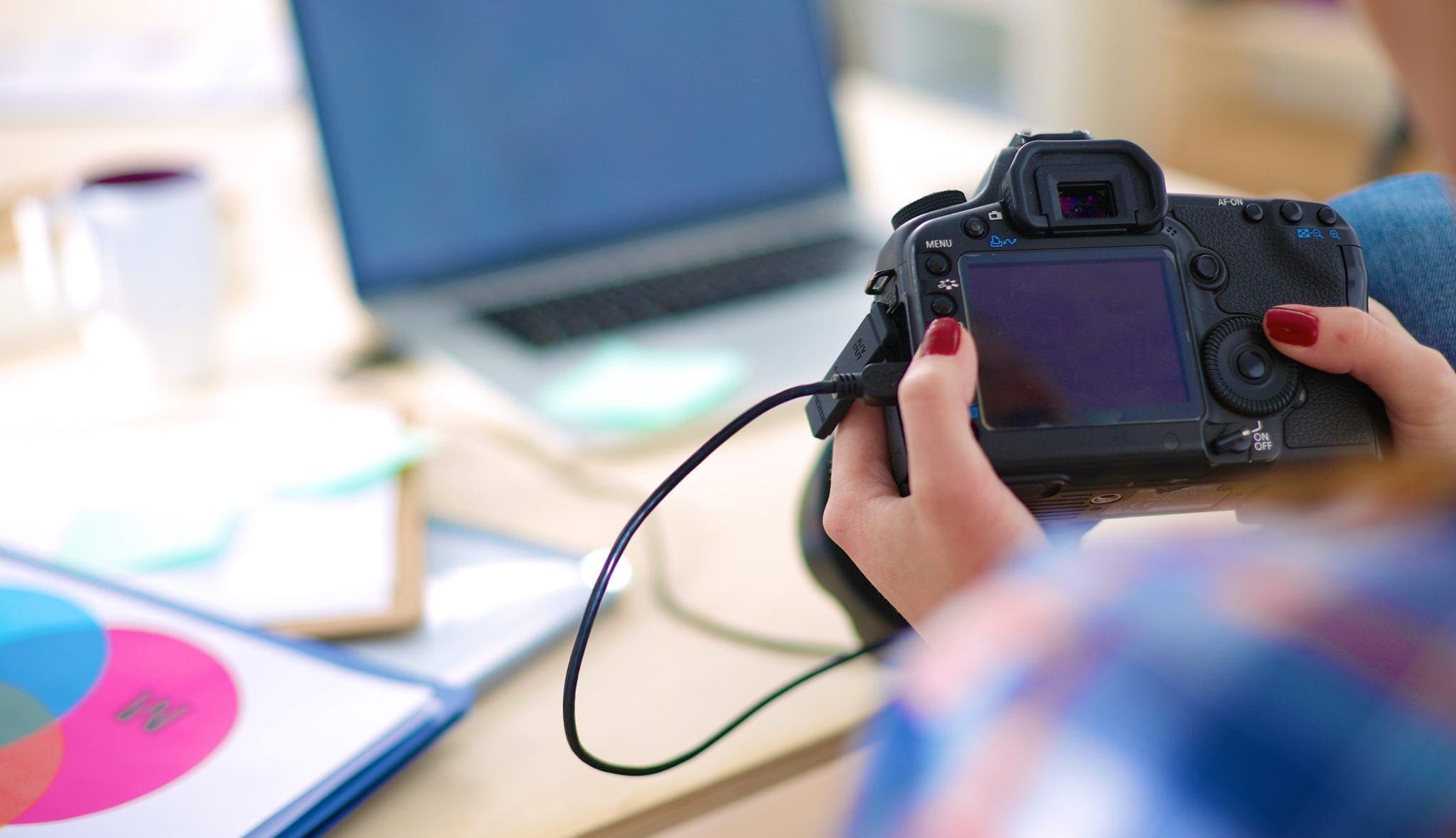 Photo of a camera being held over a desk with a laptop on it