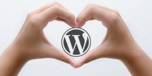 two hand making a heart image with a wordPress logo inside