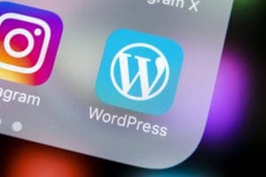 Close-up of WordPress app icon on a smartphone screen with Instagram icon beside it