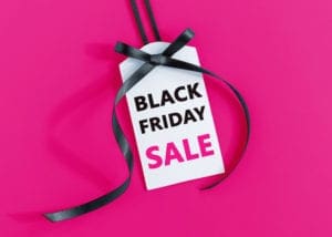 White sale tag with black ribbon on pink background displaying Black Friday Sale text