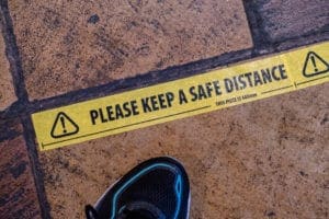 Yellow floor sticker with 'Please Keep A Safe Distance' text for social distancing