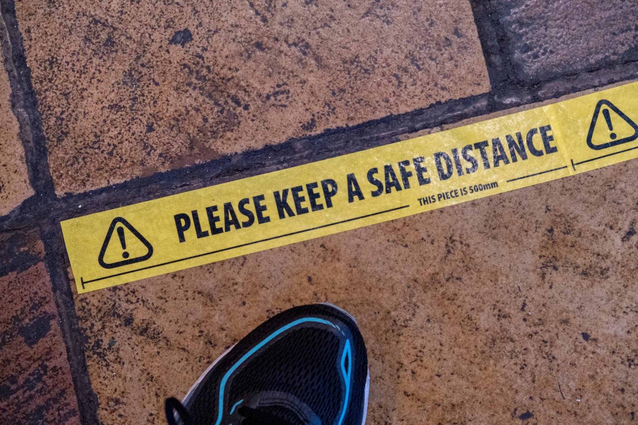 Yellow floor sticker with 'Please Keep A Safe Distance' text for social distancing