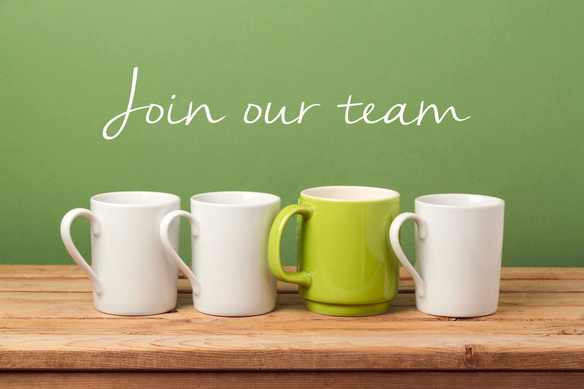 Four mugs on a table with one green mug standing out, and the text ‘Join our team’ above