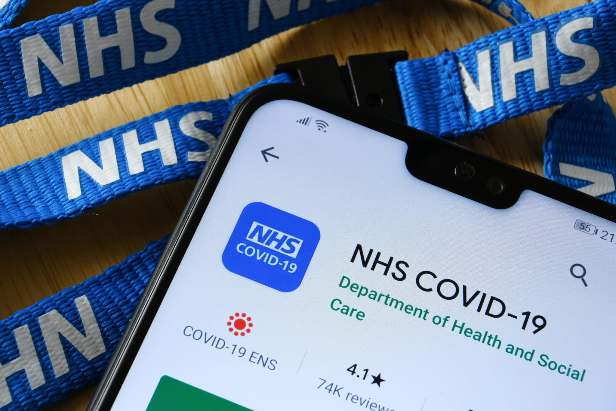Close-up of NHS COVID-19 app open on a smartphone with NHS lanyard in the background