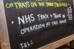 Handwritten chalkboard sign indicating NHS Track and Trace is in operation at the venue