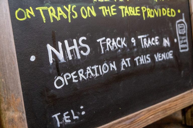 Handwritten chalkboard sign indicating NHS Track and Trace is in operation at the venue