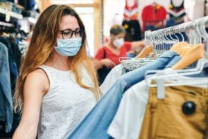 Woman wearing a face mask shopping for clothes in a store after COVID-19 restrictions ease