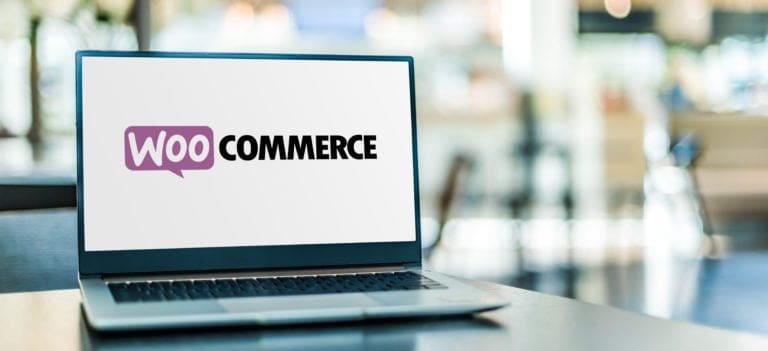 WooCommerce logo displayed on a laptop screen in a modern indoor setting.