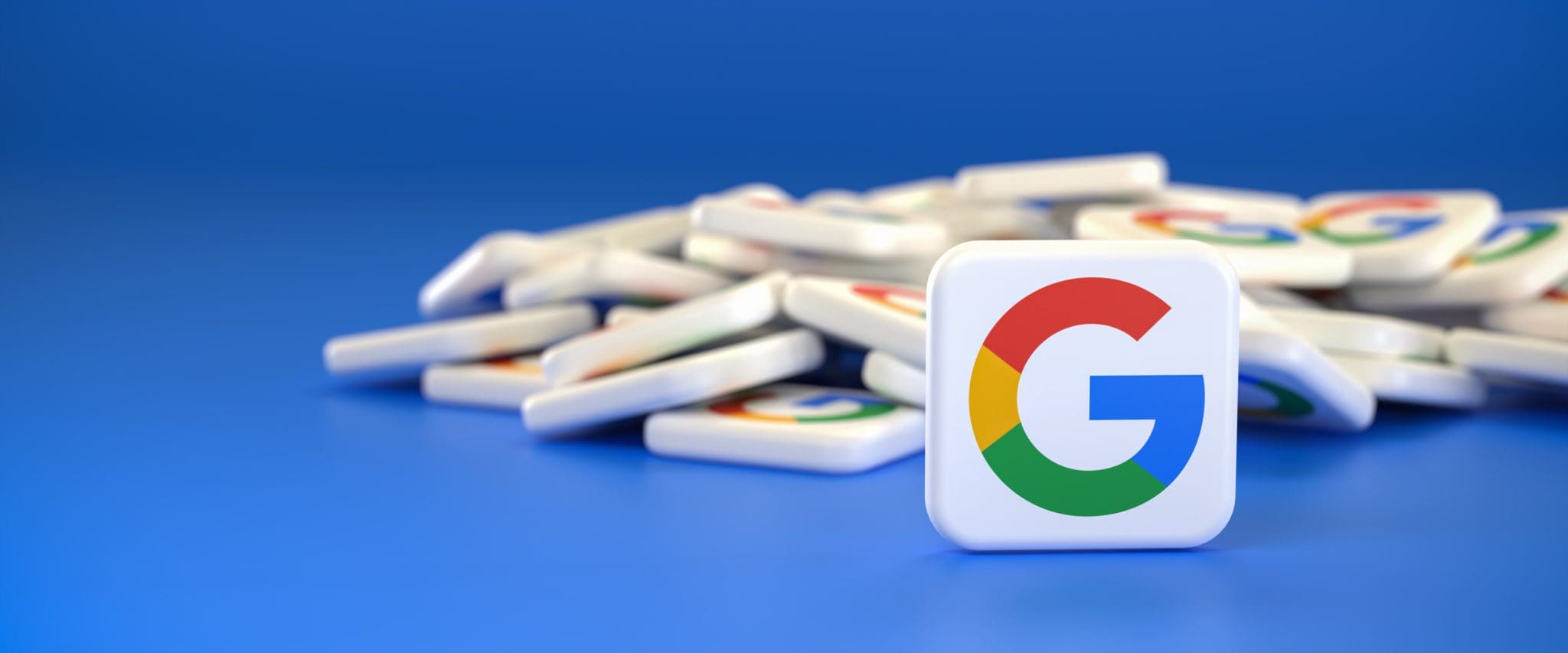 Google logo tile in focus with multiple blurred tiles in the background on a blue surface