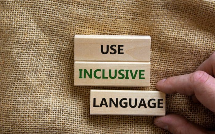 Wooden blocks spelling out “Use Inclusive Language” on a burlap background, highlighting disability-inclusive communication