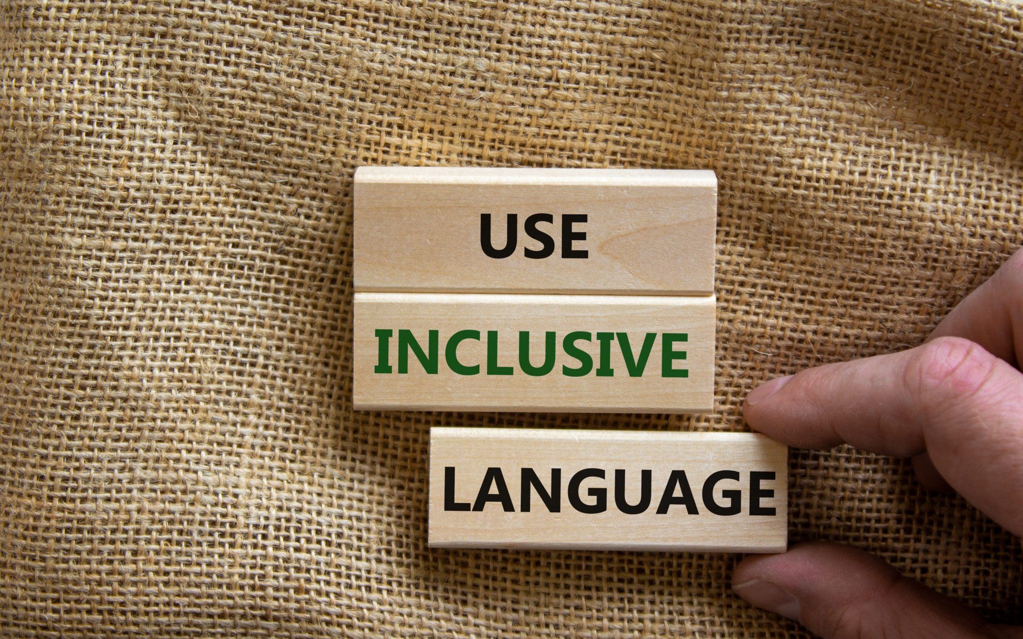 Wooden blocks spelling out “Use Inclusive Language” on a burlap background, highlighting disability-inclusive communication