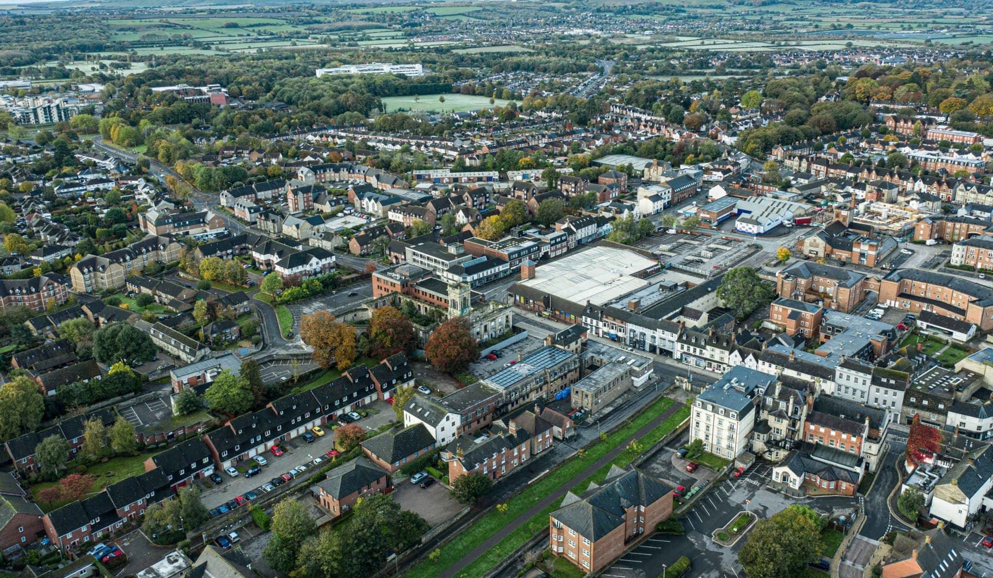 A high-angle aerial view of Swindon town centre showcasing residential and commercial buildings surrounded by greenery