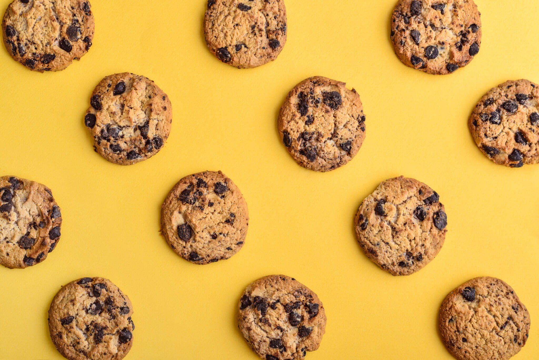 Chocolate chip cookies on a yellow background representing website cookie compliance