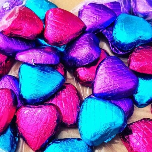 Heart-shaped chocolates in pink, purple, and blue foil wrappers – Valentines Day themed image