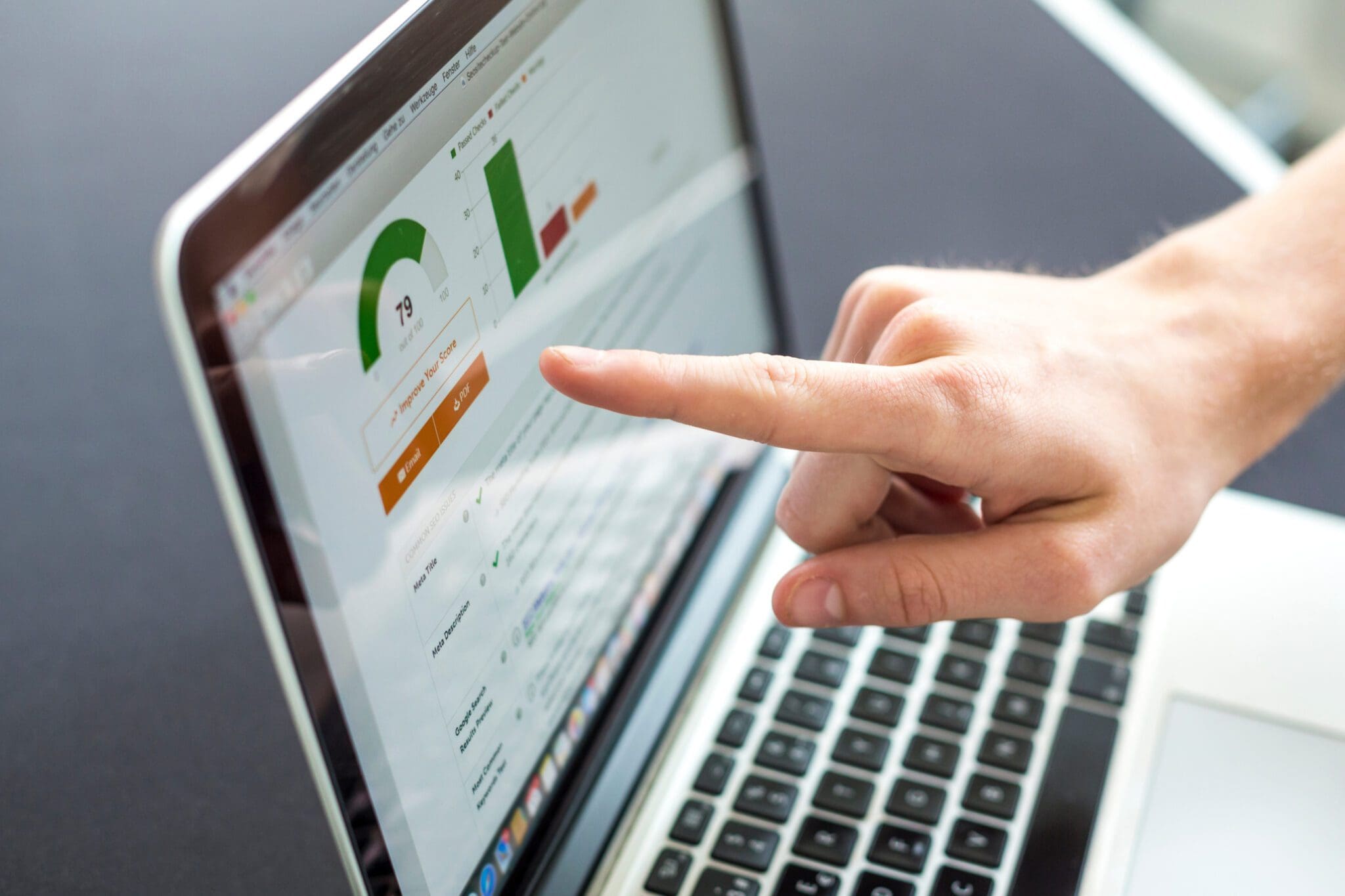 Person pointing at a laptop screen displaying website SEO performance and indexing score