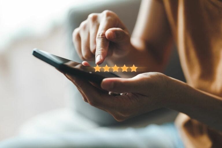 Person tapping a five-star rating on a smartphone screen, representing customer reviews