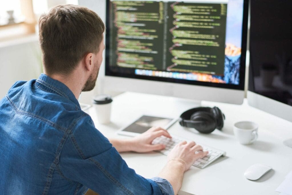 Web developer coding at a desktop computer in a bright office