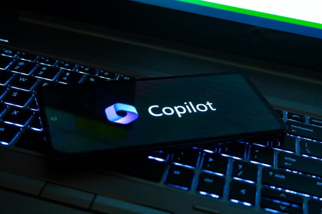 A smartphone displaying the Microsoft Copilot logo, placed on a laptop keyboard, symbolising the integration of AI in creative workflows.