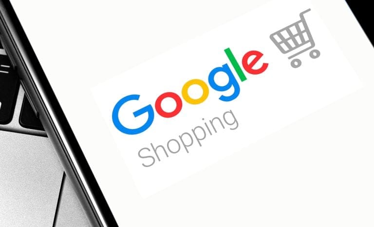 Google Shopping logo displayed on a smartphone screen next to a laptop keyboard