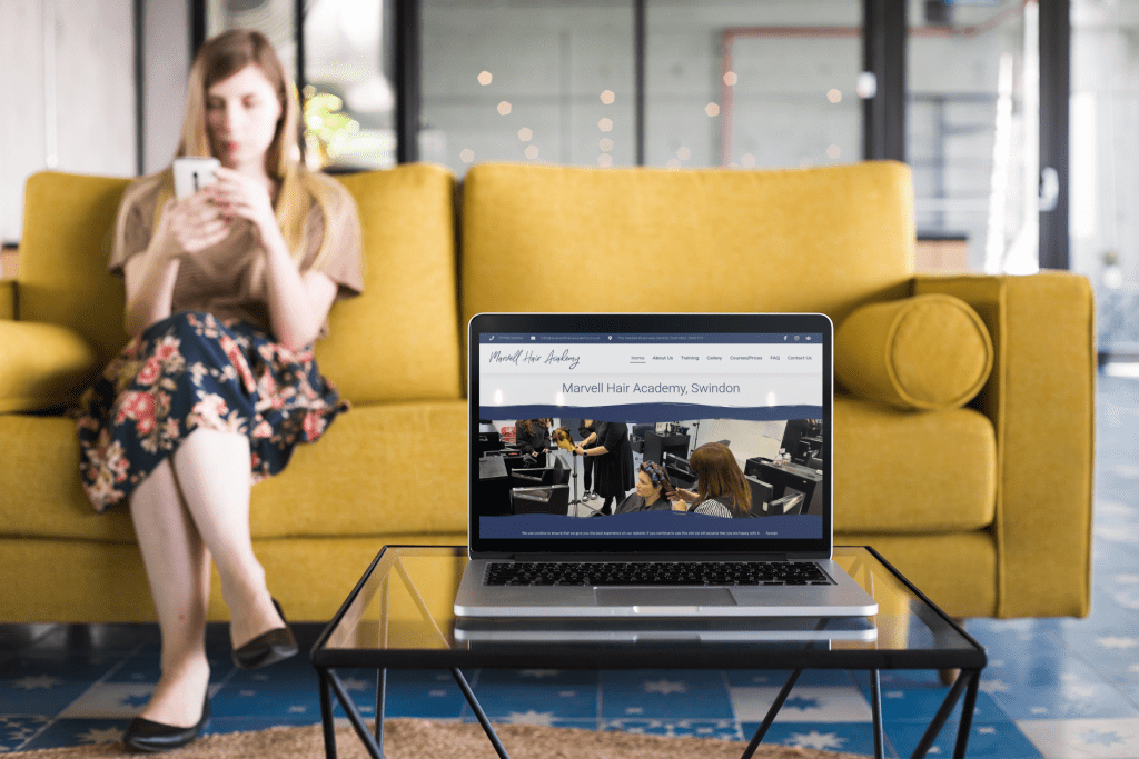 MacBook on a glass table near a person, representing a modern website in development