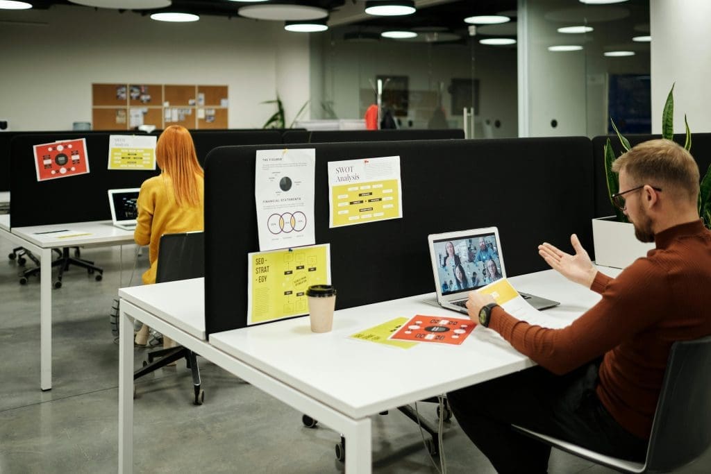 People working on laptops in a modern open-plan office with white desks